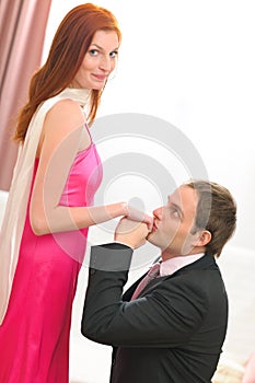 Young man in suit kissing hands of woman