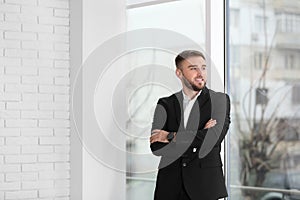 Young man in suit near window in office