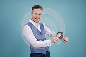 Young man in suit pointing at black alarm clock with his index finger. Business