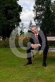 Young man in suit rest on the bench