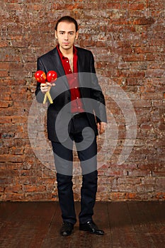 Young man in suit stands with maracas in studio photo