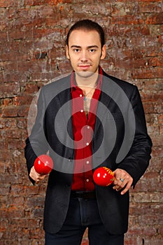 Young man in suit stands with red maracas in photo