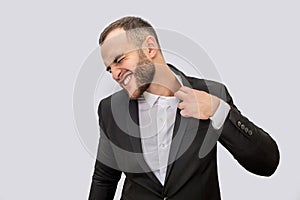 Young man in suit suffer. He holds edge of collar and pull it. Young man shrinks. Isolated on white background.