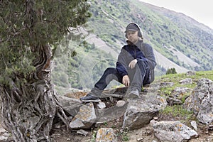 Young man in summer mountains at sunset and enjoying view of nature. Happy hiker, life goal, success, freedom and happiness