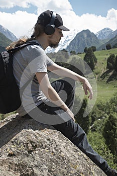 Young man in summer mountains at sunset and enjoying view of nature. Happy hiker, life goal, success, freedom and happiness