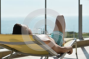 Young man sun tanning in a sunlounger