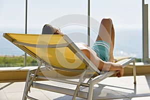 Young man sun tanning in a sunlounger