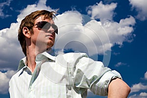 Mladý muž v sluneční brýle proti modrá obloha 