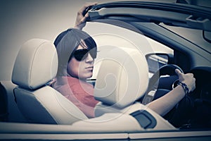 Young man in sunglasses driving convertible car