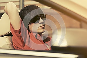 Young man in sunglasses driving convertible car