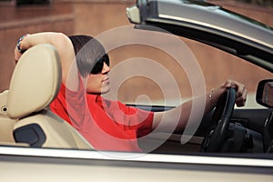 Young man in sunglasses driving convertible car