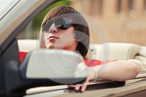 Young man in sunglasses driving convertible car