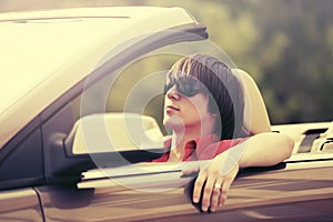 Young man in sunglasses driving convertible car