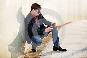 Young man in sunglasses looking at mobile phone