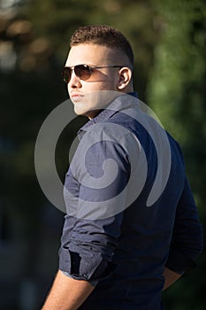 Young man in sunglasses walking in park