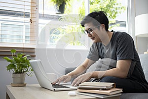 Young man surfing internet with computer laptop at home.