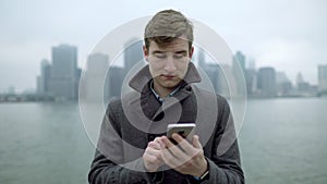 Young man surfing the Internet with Manhattan island behind his back