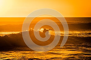 Young man surfing in the ocean at sunset
