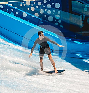 Young man surfing on a wave simulator at a water amusement park