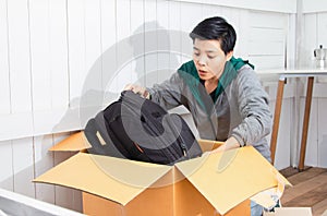 Young man surprised and unpacking the package received online shopping parcel opening boxes buying is bag