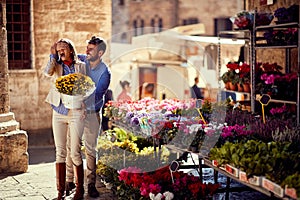 Young man surprises girl for plants at flower shop on the street