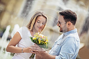 Young man surprising woman with flowers