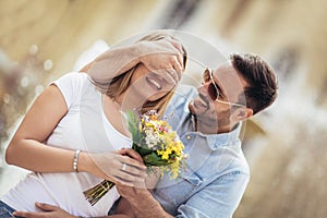 Young man surprising woman with flowers