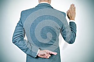 Young man swearing an oath, crossing his fingers in his back photo