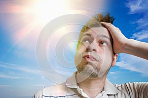 Young man is sweating. Hot weather concept. Sun in background