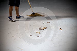 Young man sweeping dried leafs on the floor