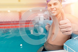 Young man swimmer showing okay thumb sign in pool, swimming competition concept