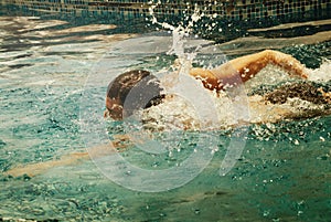 Young man swimmer train swimming in swimming pool. Recreation outdoor water sport.