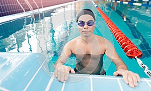 Young man swimmer wearing goggles training In swimming pool blue water