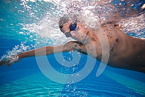 Young man swimming the front crawl in a pool