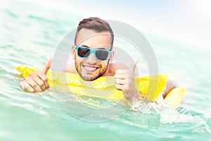 Young man swimming on a matress photo