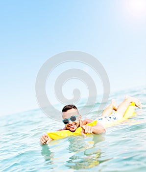 Young man swimming on a matress photo