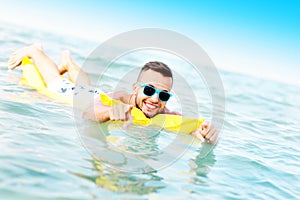 Young man swimming on a matress photo