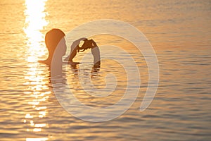 young man swimming in sea at sunset