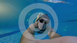 Young man swimming underwater holding a camera
