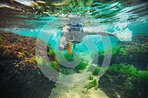 Young man, swimming underwater and making photos with sport camera