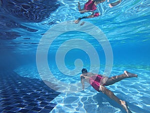 Young man swimming underwater in the pool