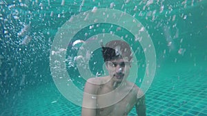 Young man swimming underwater waterdrops falling and splashing in amazing blue ocean. slow motion. 120fps. 1920x1080