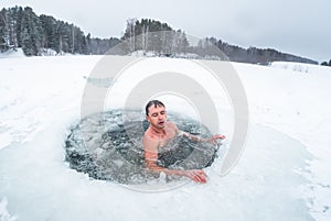 Young man swims in the ice hole