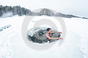 Young man swims in the ice hole