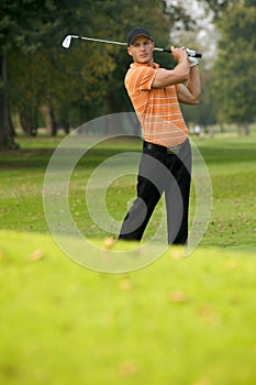 Young man swinging golf club