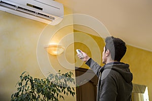 Young man switching on the air conditioner