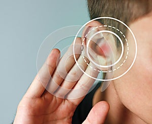 Young man with symptom of hearing loss on color background photo