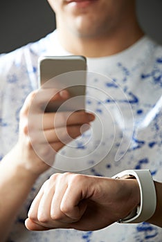 Young Man Synchronizing Smart Watch With Mobile Phone