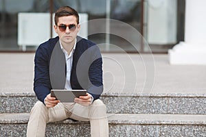 Young man with tablet computer sitting on stairs