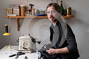 Young man tailor smiling at workplace in sewing workshop